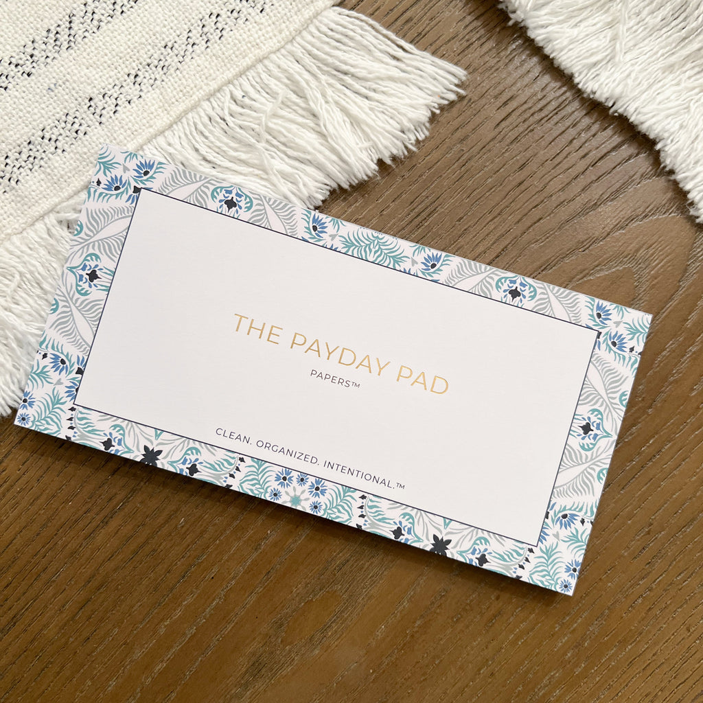 A sleek, portable budgeting pad named 'The Payday Pad' with elegant gold foiling, 